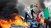 Pengunjuk rasa melambaikan bendera dari atas mobil yang rusak saat bentrok dengan penegak hukum di jalan-jalan di sekitar gedung federal selama protes setelah operasi imigrasi federal di Los Angeles, California, Amerika Serikat pada 8 Juni 2025. (RINGO CHIU/AFP)